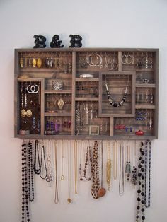 a wall mounted jewelry organizer with lots of necklaces and earrings hanging on it's sides