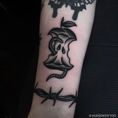 an apple and barbed wire tattoo on the arm