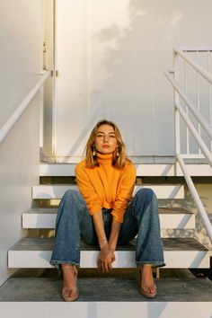 a woman sitting on some steps with her legs crossed and looking up at the camera