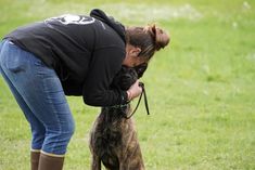 a woman is petting her dog in the park