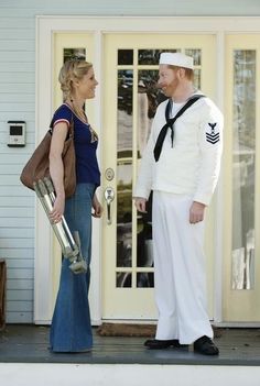 a man and woman in sailor costumes standing on the front steps of a house talking to each other