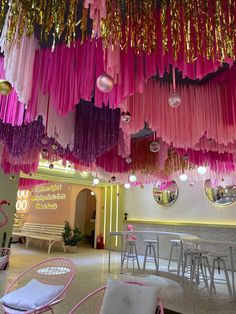 pink and gold streamers hanging from the ceiling in a room filled with tables and chairs