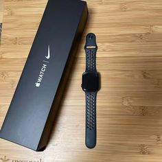 an apple watch sitting on top of a wooden table next to a box and pen