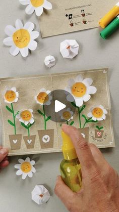 someone is holding a bottle with flowers on it and paper cut outs surrounding the image