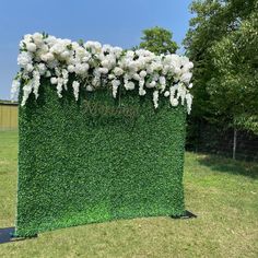 an artificial hedge wall with white flowers on it