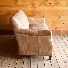 a brown leather chair sitting on top of a wooden floor next to a wood wall