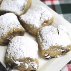 a white plate topped with pastries covered in powdered sugar on top of a checkered table cloth