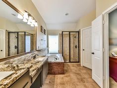 a large bathroom with marble counter tops and tile flooring, along with double sinks