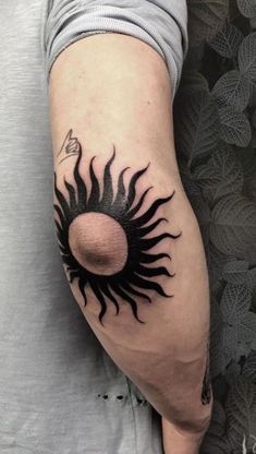 a man's arm with a sun tattoo on the left side of his arm