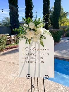 a welcome sign with flowers on it in front of a swimming pool