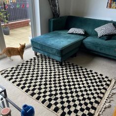 a living room with a green couch and black and white rug