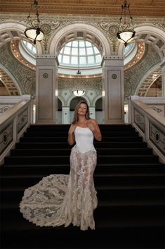 a woman in a white dress standing on some stairs