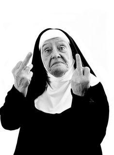 a nun holding her hands up in front of her face and making the peace sign