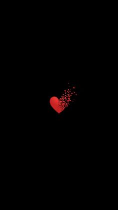 a red heart with sprinkles on it in the black sky at night