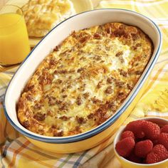 a casserole dish with meat and cheese in it next to raspberries