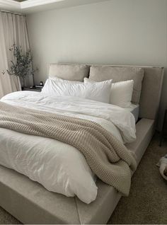 a bed with white sheets and pillows in a bedroom