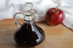 an apple sitting next to a glass carafe on top of a wooden table