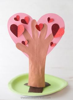 a paper heart shaped tree on top of a green planter with hearts cut out of it