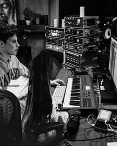 a young man sitting in front of a computer keyboard and sound mixing equipment on a desk