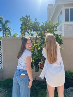 two young women standing in front of a lemon tree