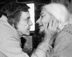 black and white photograph of an older woman hugging the face of a younger man who is wearing a jacket