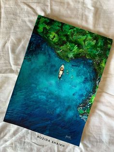 an aerial view of a small boat in the blue water surrounded by greenery and trees