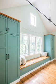 an empty room with blue cabinets and white pillows on the window sill, along with hardwood flooring