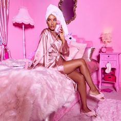 a woman sitting on top of a bed in a pink room