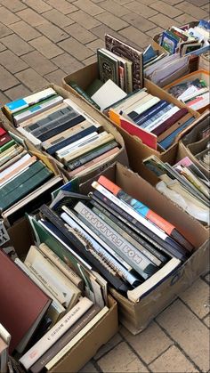 several boxes filled with books sitting on top of a brick floor next to each other