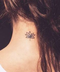 a woman's neck with a small lotus tattoo on the back of her neck