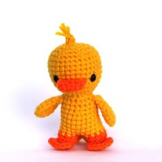 a crocheted yellow duck sitting on top of a white surface