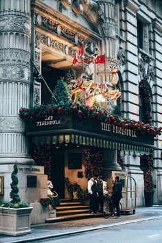 people are standing in front of a building decorated for christmas