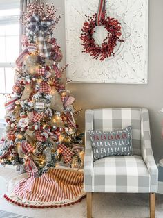 a decorated christmas tree in the corner of a living room next to a plaid chair