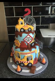 a three tiered cake with construction vehicles on it