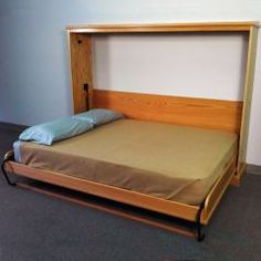 a bed with a wooden headboard and blue pillow on it's side in a room