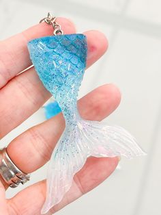 a hand holding a blue and white fish shaped keychain