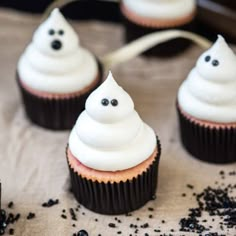 cupcakes with white frosting and black sprinkles on a table