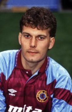 a young man sitting on top of a soccer field wearing a blue and red shirt