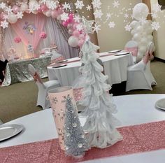 a table with pink and silver decorations on it, white tables cloths and balloons