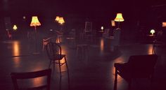 several chairs and lamps in a dark room with no one sitting at the table or standing up