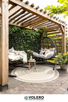 an outdoor area with a swing chair, table and potted plants on the ground