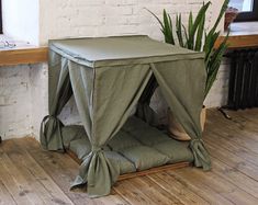 a green tent sitting on top of a wooden floor next to a potted plant