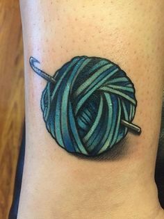 a ball of yarn on the ankle with scissors in it and an arrow tattoo design