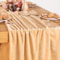 the table is set with plates and napkins on it, along with an arrangement of flowers