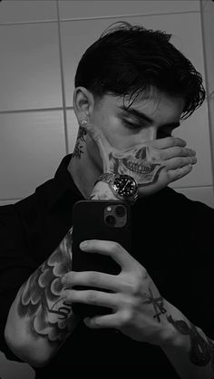 a man taking a selfie with his cell phone in front of him and tattoos on his arms