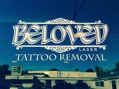 the logo for beloved laser tattoo removal in front of a store window with cars parked outside