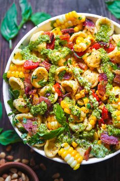 a bowl filled with pasta, broccoli and other vegetables on top of a wooden table