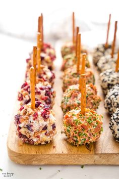 an assortment of appetizers are arranged on a cutting board with toothpicks