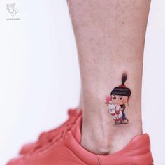 a small tattoo on the ankle of a girl with a pony tail in her hair