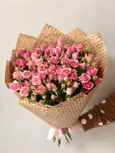 a bouquet of pink roses is held by someone's hand with brown leather gloves